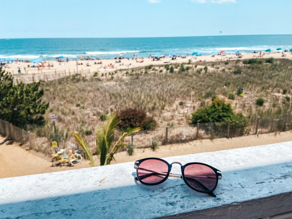 sunglasses on wooden railing looking out on the beach and ocean