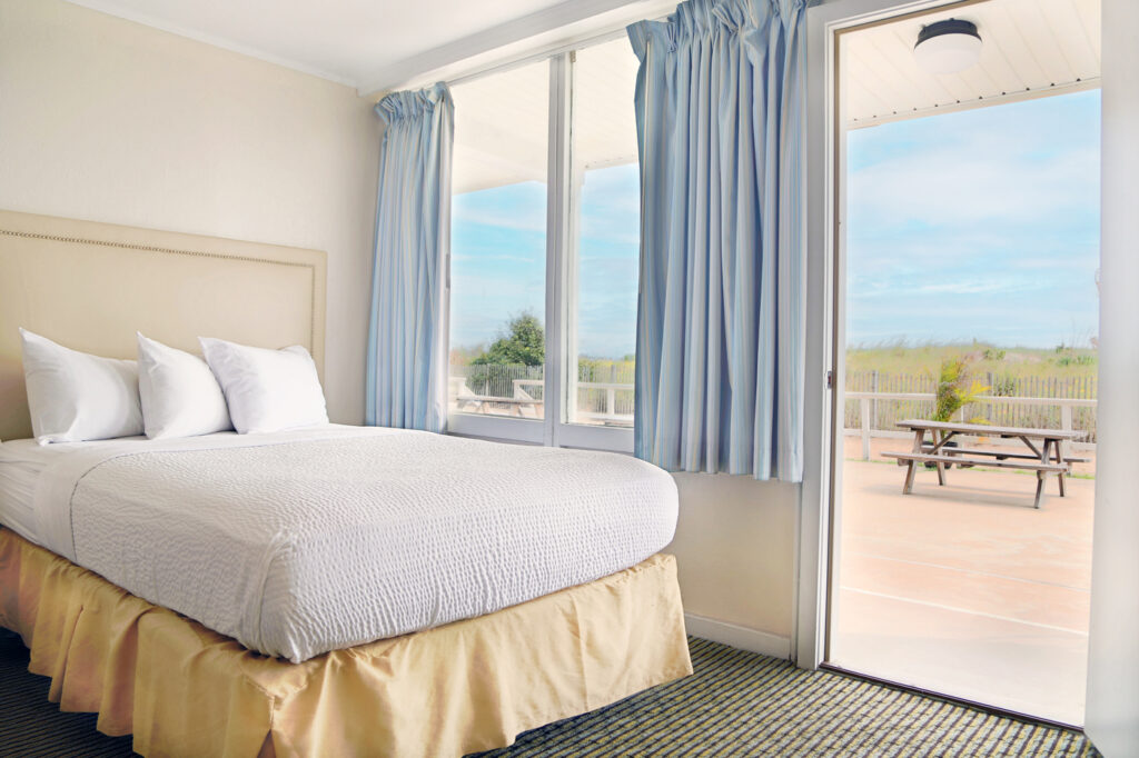 inside motel room with bed and oceanfront view in background