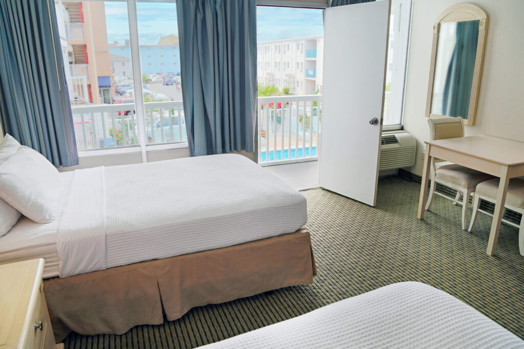 inside motel room with 2 beds and oceanfront view and pool in background